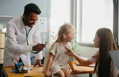 Photo d'un pédiatre communautaire avec un patient et sa mère.