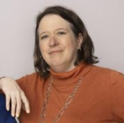 Woman with dark hair and orange sweater